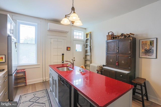 kitchen featuring a sink, dishwasher, a wall unit AC, wood finished floors, and freestanding refrigerator