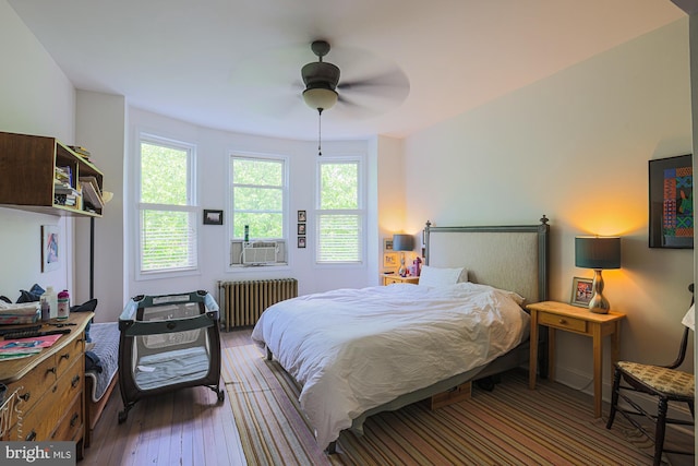 bedroom featuring radiator heating unit, hardwood / wood-style flooring, and a ceiling fan