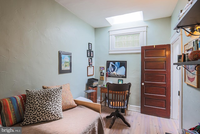 sitting room featuring a skylight, hardwood / wood-style floors, and baseboards