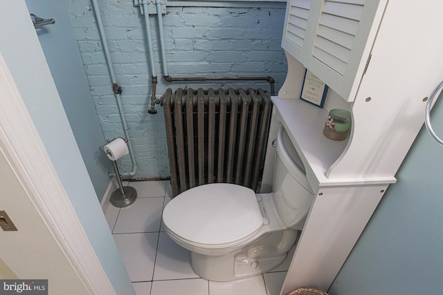 bathroom featuring radiator heating unit, tile patterned flooring, toilet, and brick wall
