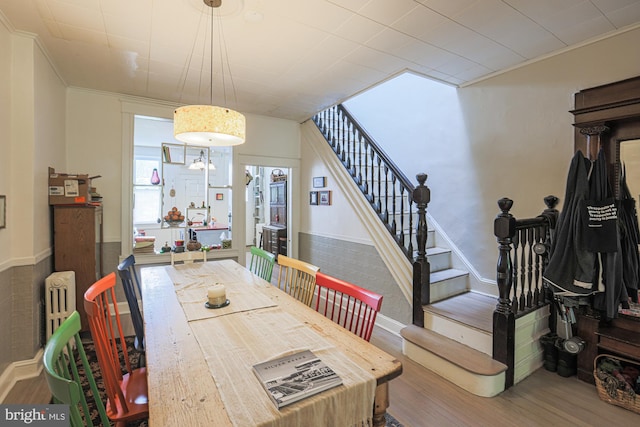 dining room with wood finished floors, stairs, plenty of natural light, ornamental molding, and radiator heating unit