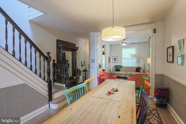 dining area with wood finished floors, stairway, baseboards, and crown molding
