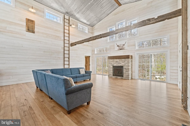 living area with high vaulted ceiling, hardwood / wood-style flooring, a healthy amount of sunlight, and wooden walls