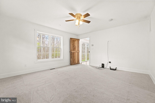spare room with carpet floors, visible vents, baseboards, and ceiling fan