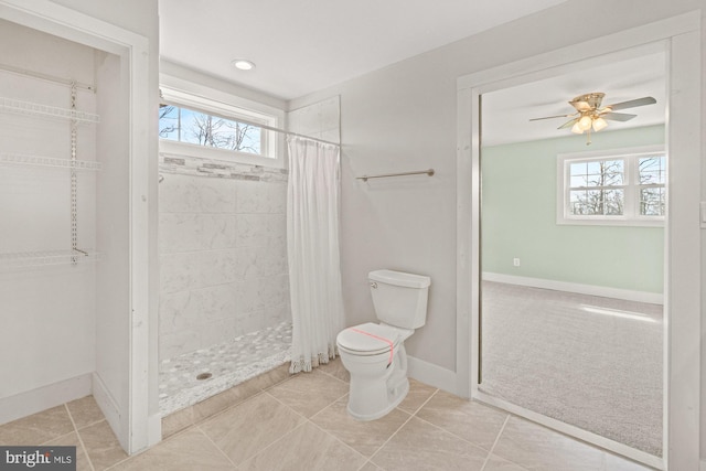 bathroom featuring toilet, baseboards, a ceiling fan, and tiled shower