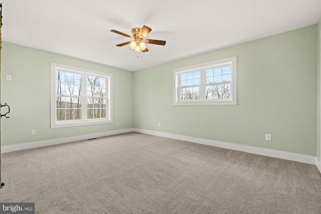 carpeted empty room featuring baseboards and a ceiling fan