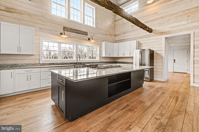 kitchen featuring wood walls, stainless steel appliances, a towering ceiling, and a kitchen island