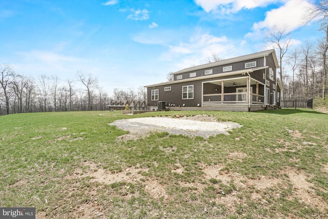 back of property with central air condition unit, a sunroom, a yard, and a ceiling fan