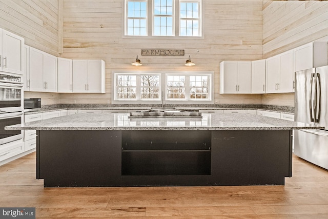 kitchen with white cabinets, light stone countertops, stainless steel appliances, and a kitchen island