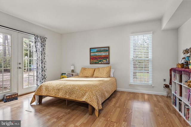 bedroom with wood finished floors, baseboards, access to outside, and french doors