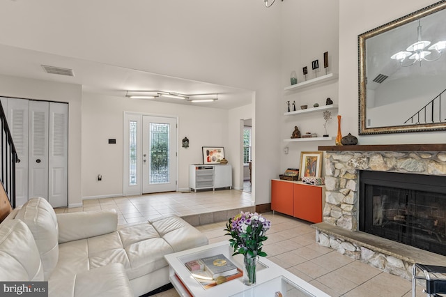 living room with baseboards, a fireplace, a notable chandelier, and light tile patterned flooring