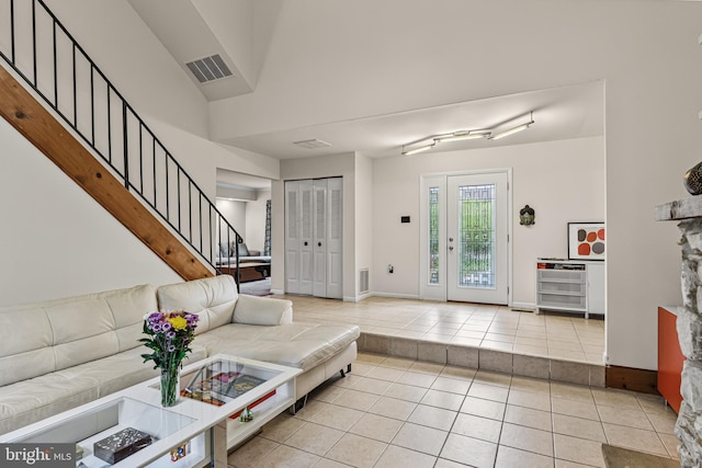 tiled living area with baseboards, stairs, and visible vents