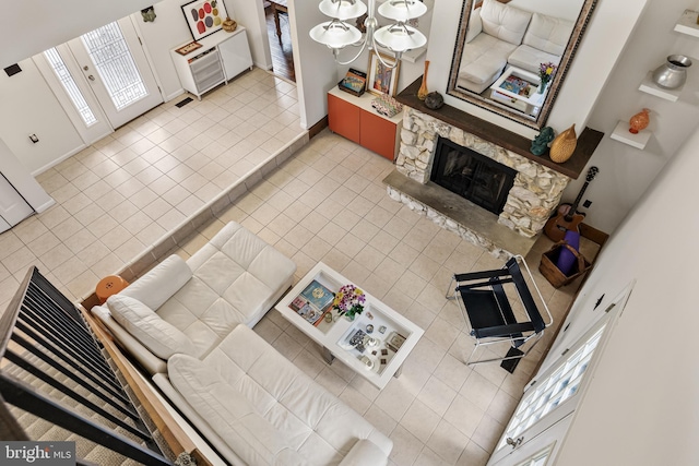 living area featuring a stone fireplace, baseboards, and light tile patterned floors