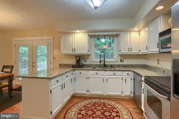 20 Tower Rd, Dillsburg, PA 17019 - kitchen with appliances with stainless steel finishes, a peninsula, light wood-type flooring, white cabinets, and light stone countertops
