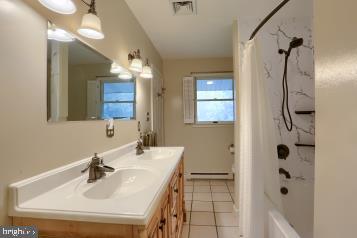 20 Tower Rd, Dillsburg, PA 17019 - full bathroom featuring double vanity, a baseboard radiator, tile patterned flooring, and shower / bath combo