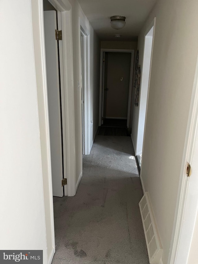 corridor featuring visible vents, baseboards, and carpet flooring