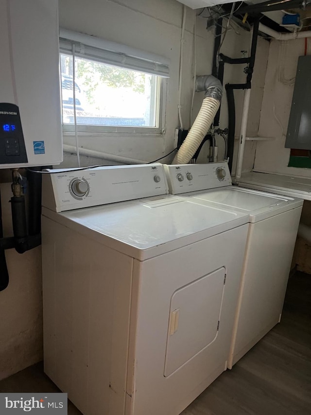 clothes washing area featuring electric panel, separate washer and dryer, laundry area, and wood finished floors