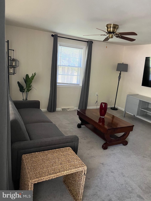 living room featuring carpet flooring, baseboards, a ceiling fan, and visible vents