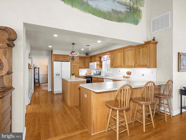 kitchen with visible vents, a center island, white appliances, and light wood-type flooring
