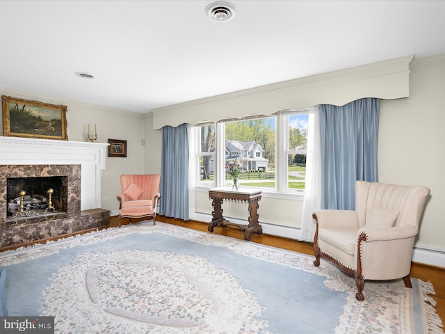 living area featuring visible vents, ornamental molding, wood finished floors, and a high end fireplace