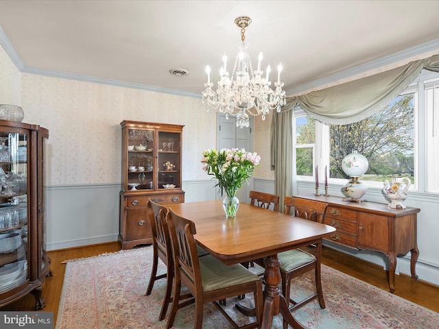 dining space with an inviting chandelier, wood finished floors, visible vents, and wallpapered walls