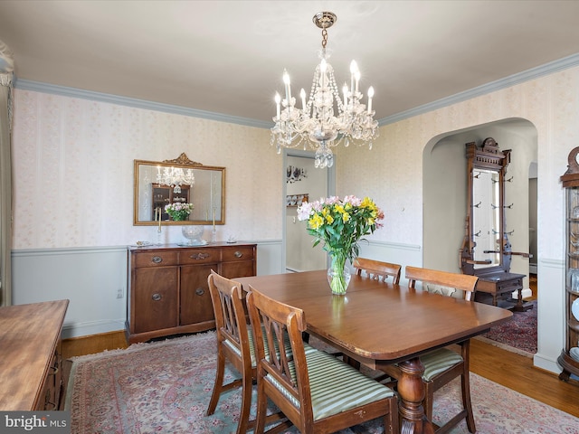 dining room with arched walkways, wood finished floors, a notable chandelier, and wallpapered walls