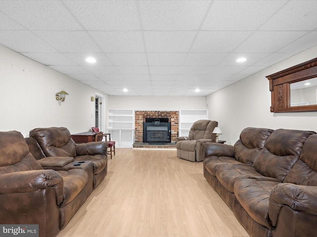 living room with a brick fireplace, recessed lighting, a paneled ceiling, and wood finished floors