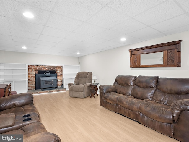 living area featuring a paneled ceiling, recessed lighting, built in features, and wood finished floors