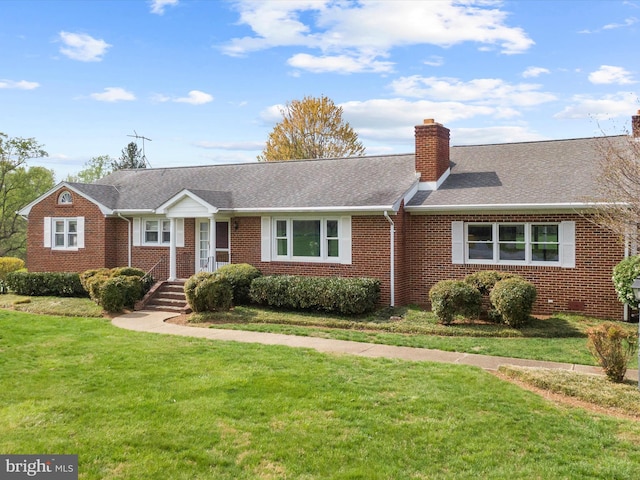 ranch-style house with brick siding, a chimney, roof with shingles, and a front lawn