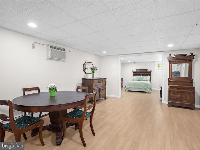 dining space with a paneled ceiling, baseboards, an AC wall unit, light wood finished floors, and recessed lighting