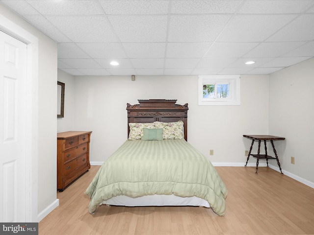 bedroom with baseboards, recessed lighting, light wood-style flooring, and a drop ceiling