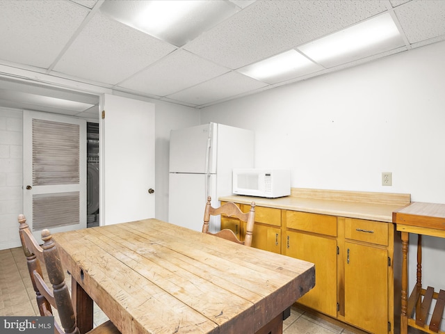 dining space featuring light tile patterned flooring and a drop ceiling