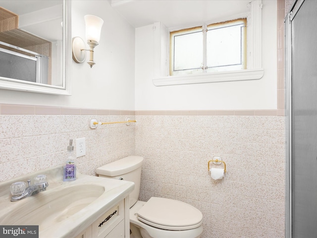 full bathroom featuring vanity, toilet, a wainscoted wall, tile walls, and a shower stall