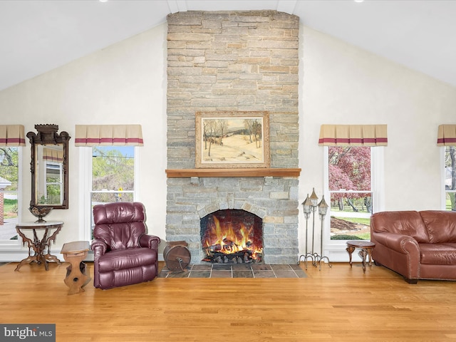 living area featuring high vaulted ceiling, wood finished floors, a wealth of natural light, and a fireplace