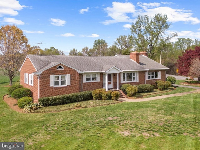 ranch-style home featuring a chimney, a front yard, and brick siding