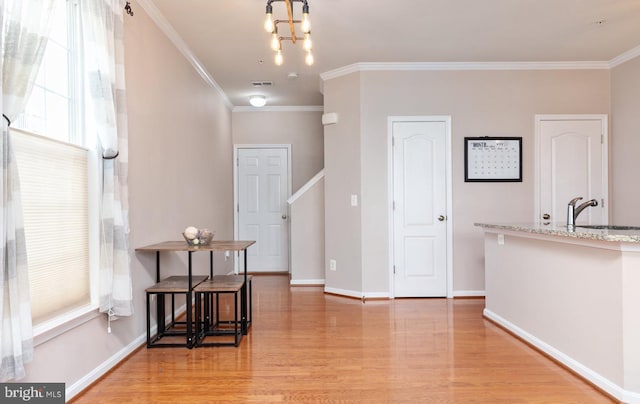 dining area with a wealth of natural light, crown molding, an inviting chandelier, and light wood-style flooring