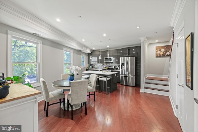 dining area featuring dark wood-type flooring, baseboards, and crown molding