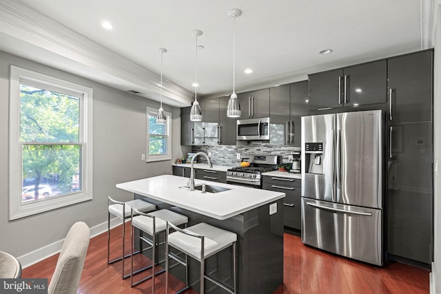 kitchen with decorative backsplash, a sink, baseboards, stainless steel appliances, and an island with sink