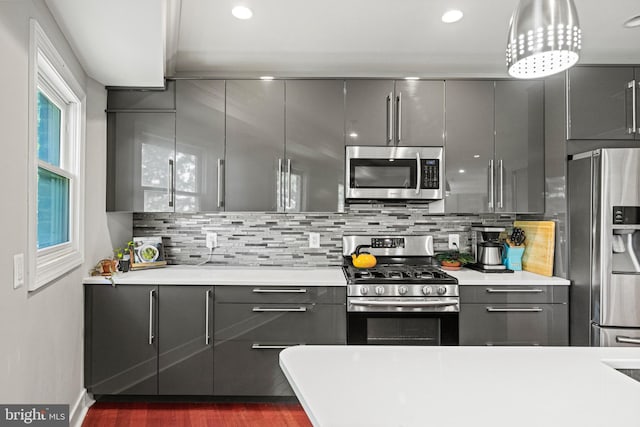 kitchen with gray cabinets, modern cabinets, tasteful backsplash, light countertops, and stainless steel appliances