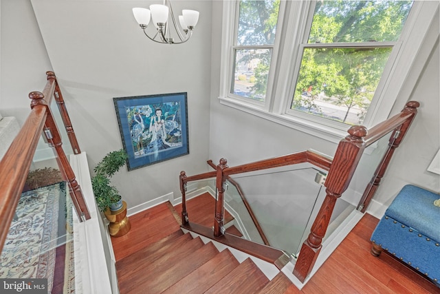 staircase featuring baseboards, a chandelier, and wood finished floors