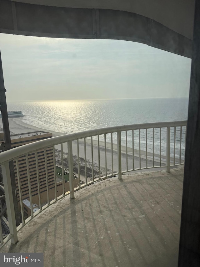 balcony featuring a view of the beach and a water view