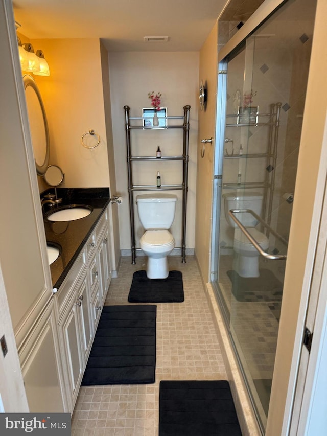 bathroom with double vanity, a shower stall, toilet, and a sink