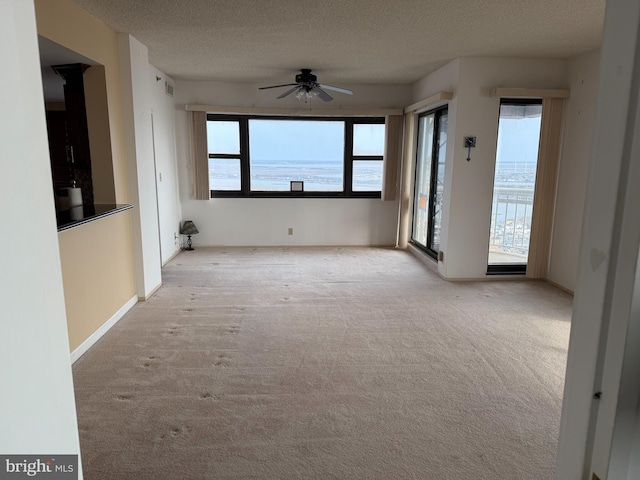 spare room with carpet floors, a textured ceiling, baseboards, and ceiling fan