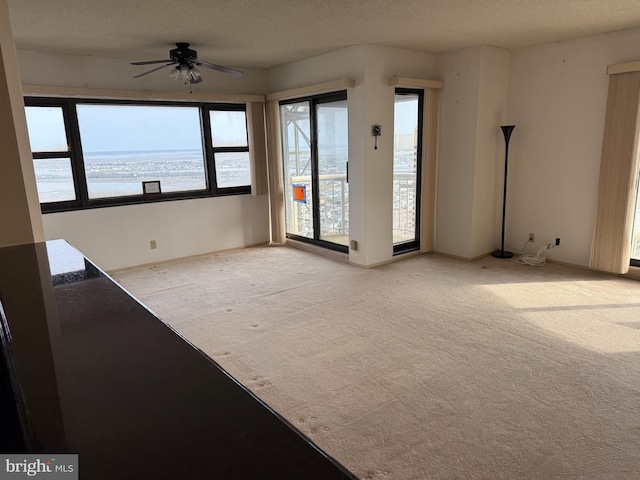 spare room with a textured ceiling, a ceiling fan, and light carpet