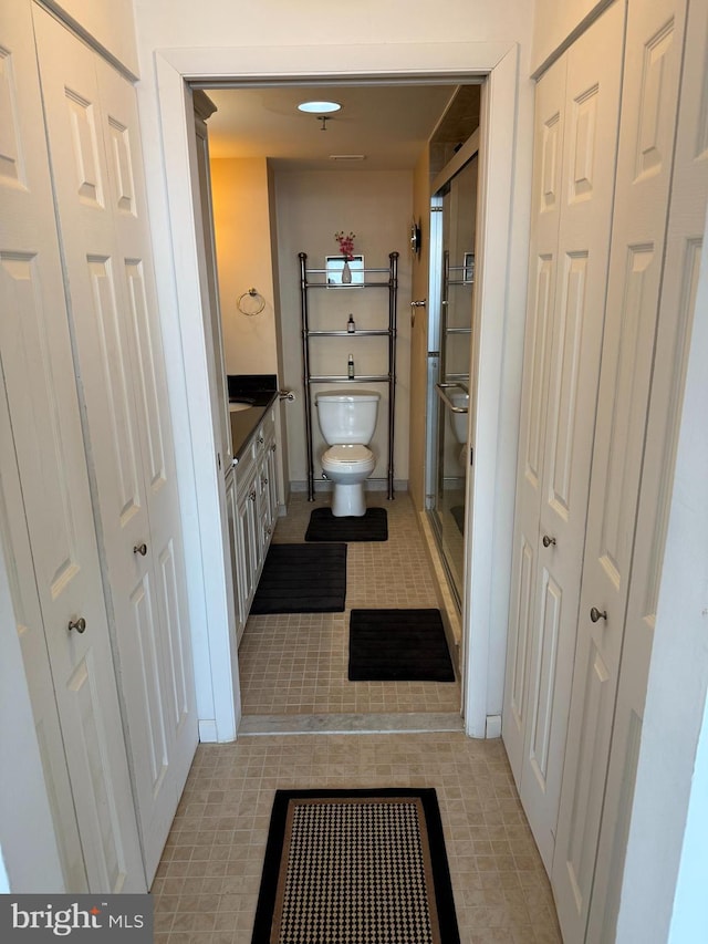 full bathroom featuring a shower stall, toilet, vanity, and a closet