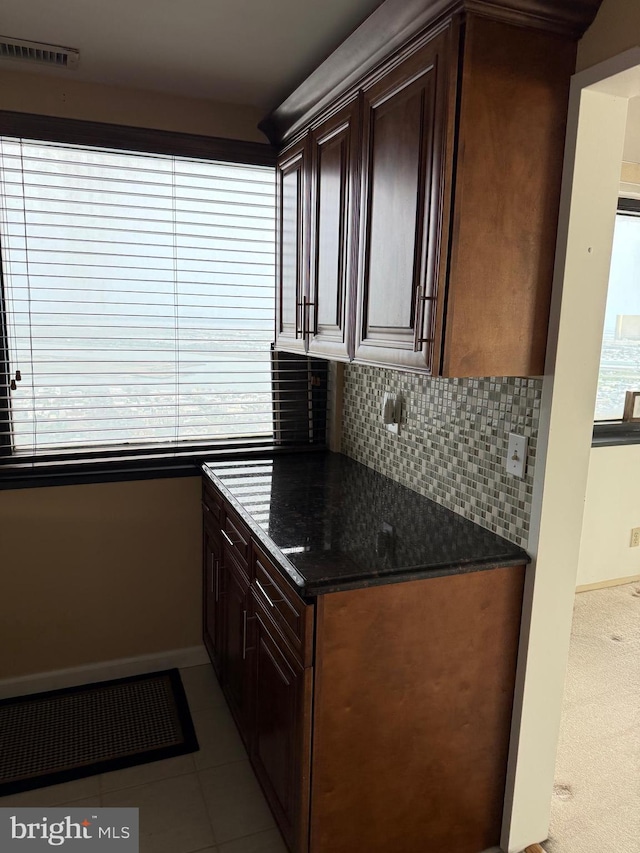kitchen featuring dark brown cabinets, tasteful backsplash, visible vents, and baseboards