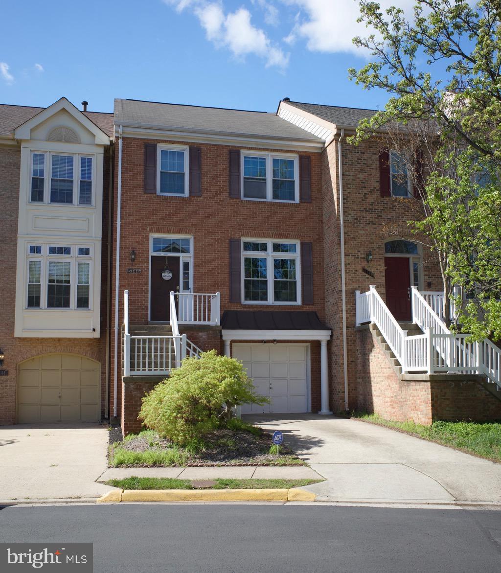 view of property with a garage, brick siding, and driveway