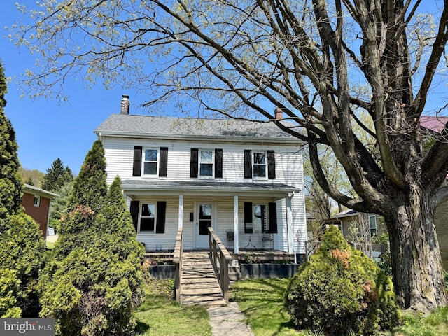 traditional home featuring covered porch and a chimney