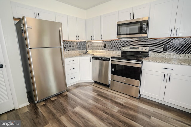kitchen with appliances with stainless steel finishes, a sink, dark wood finished floors, and backsplash