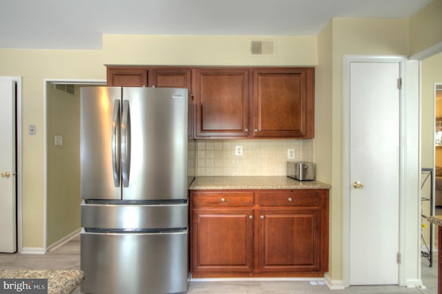 kitchen featuring freestanding refrigerator, baseboards, visible vents, and decorative backsplash